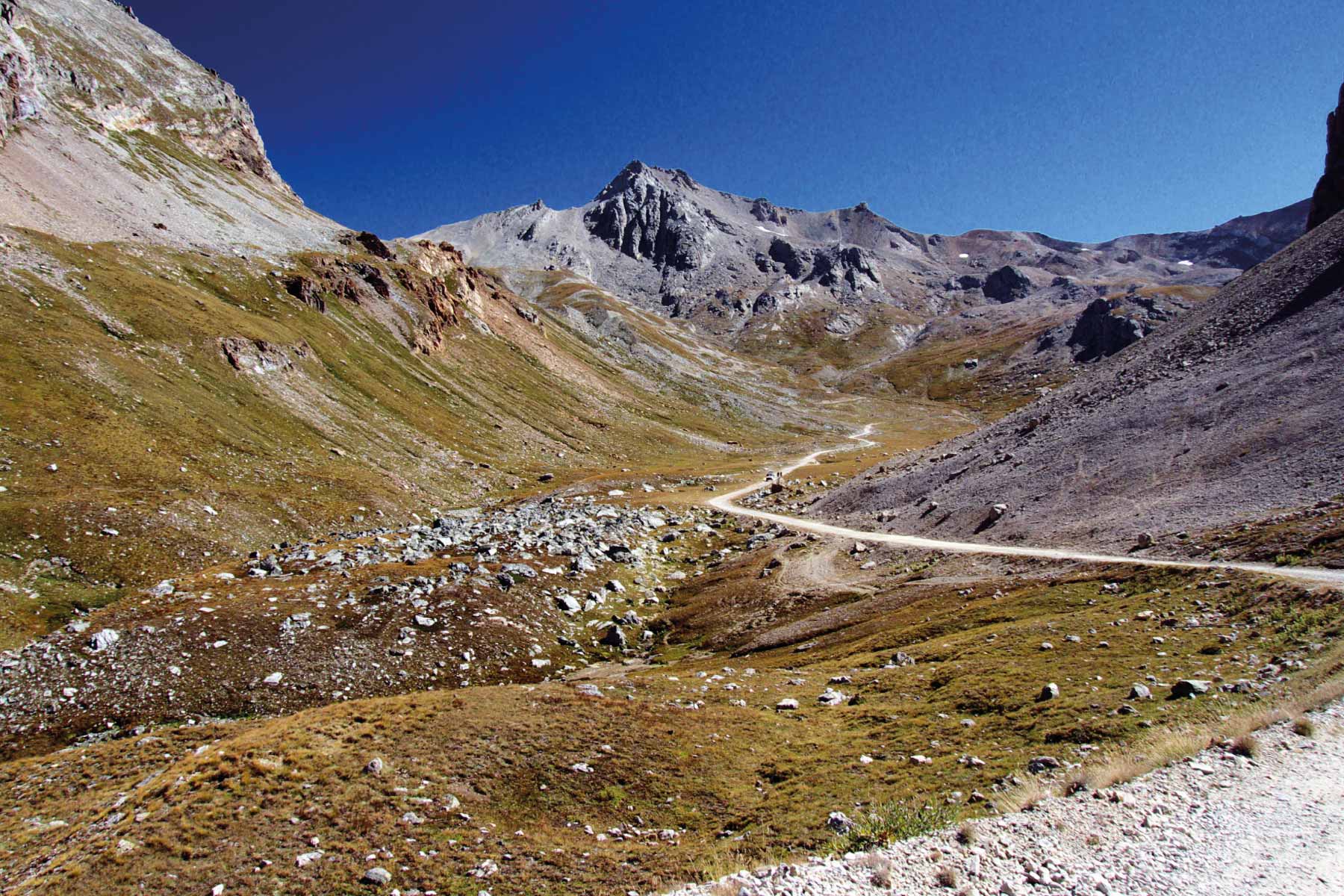 Percorso sterrato tra montagne con cielo sereno