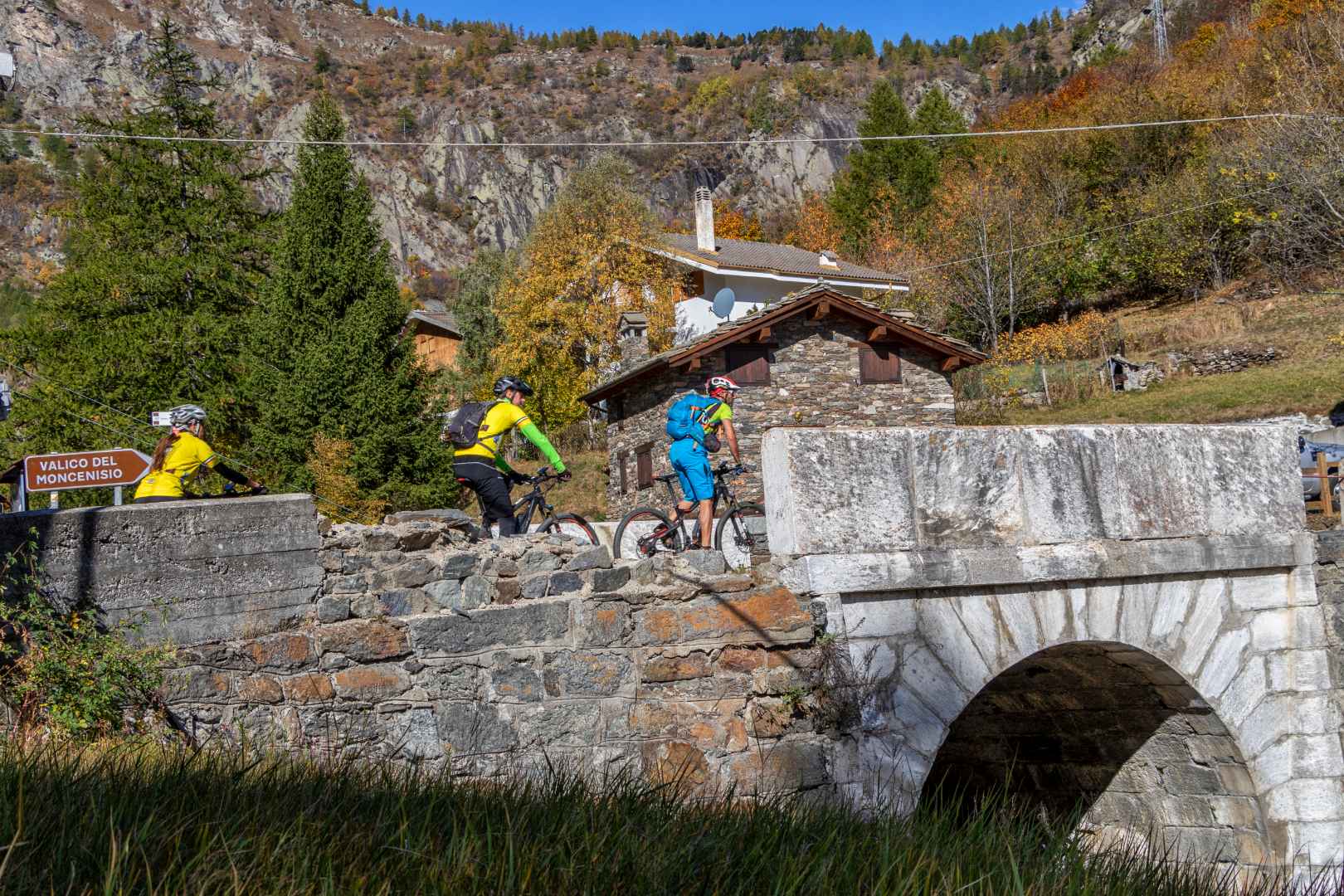 Ciclisti percorrono una strada di montagna attraversando un piccolo ponte