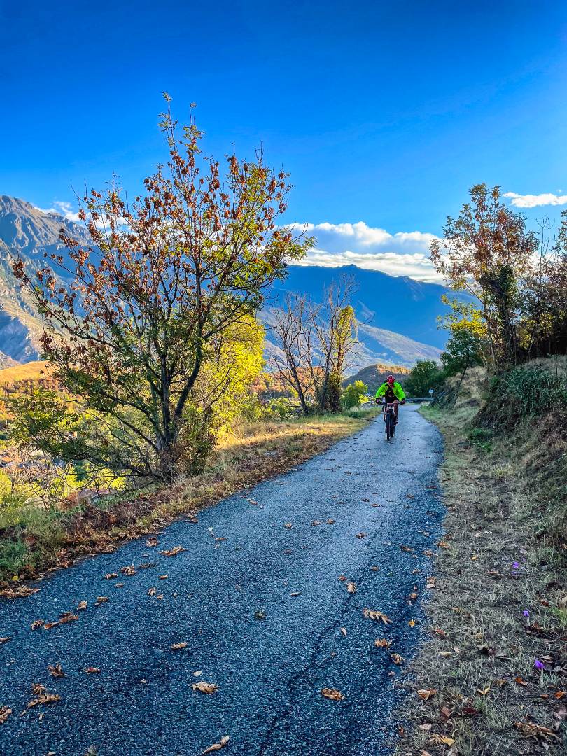 "Ciclista solitario su strada montana autunnale."