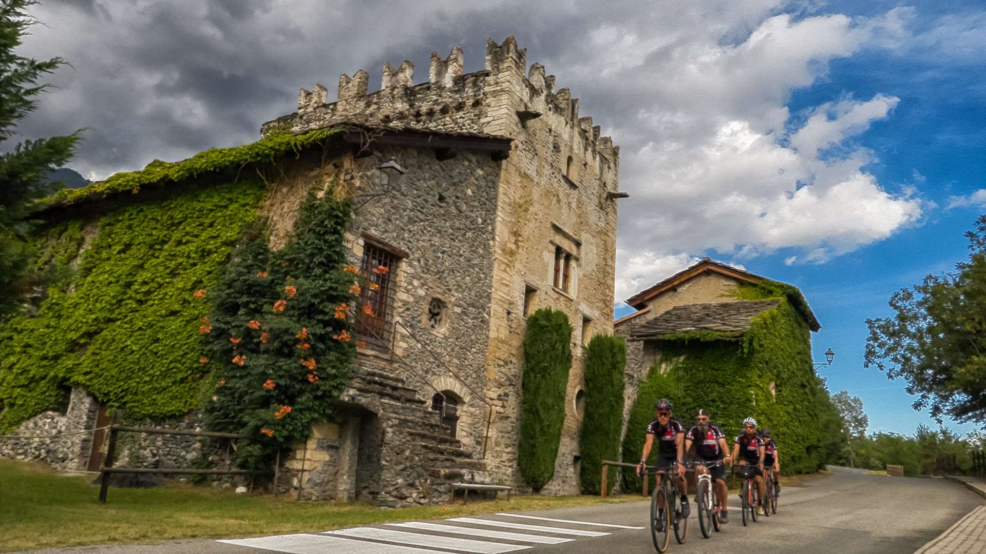 Ciclisti in corsa vicino ad antica casa