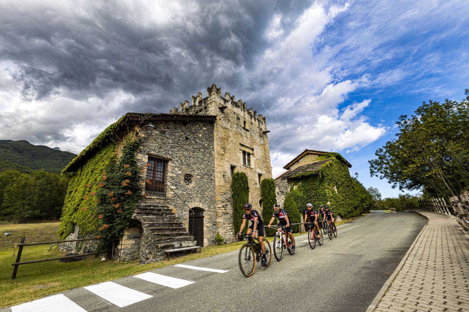 Ciclisti in corsa vicino ad antica casa